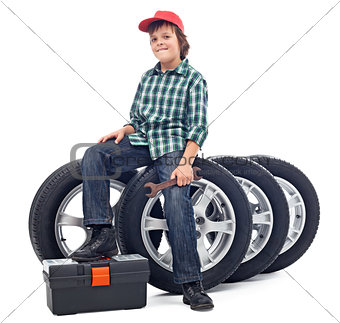 Boy sitting on car tires