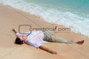 Tired man lie on sandy beach