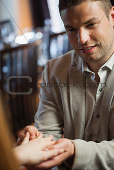 Handsome man putting on ring on his fiances finger
