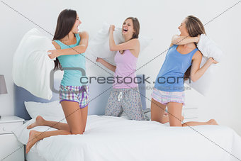 Girls in bed having pillow fight in pajamas