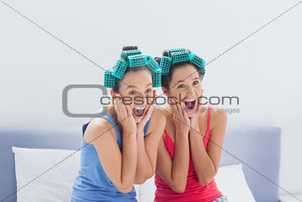 Friends with hair rollers on sitting in bed