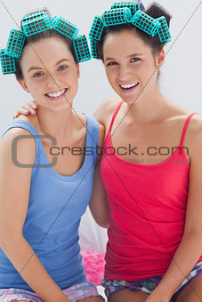 Girls in hair rollers sitting in bed and smiling