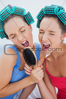 Friends in hair rollers holding hairbrush