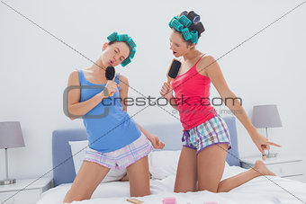 Girls in hair rollers singing with hairbrush