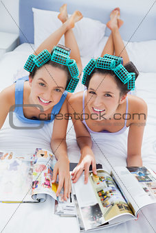 Happy friends in hair rollers lying in bed