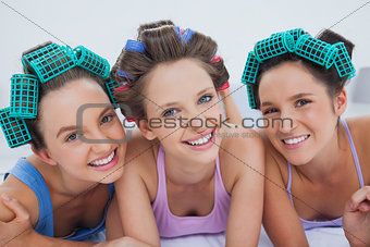 Friends in hair rollers and pajamas lying in bed