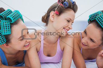 Girls in hair rollers relaxing in bed and talking