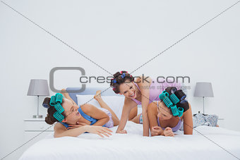 Girls in hair rollers having fun in bed