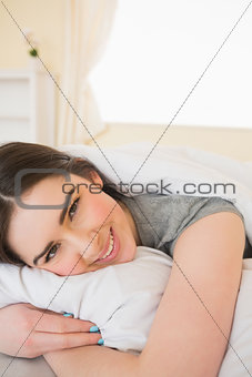 Smiling brunette relaxing in her bed