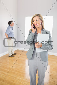 Smiling realtor calling someone with her mobile phone