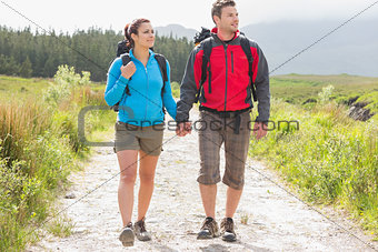 Hikers with backpacks holding hands and walking