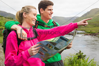 Athletic couple in hooded jumpers on a hike holding map
