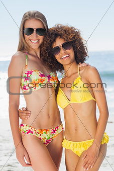 Two pretty friends in bikinis wearing sunglasses posing