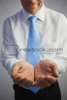 Close up of a smiling businessman joining his hands to the camera