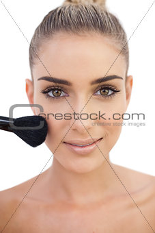 Smiling woman applying powder on her cheeks