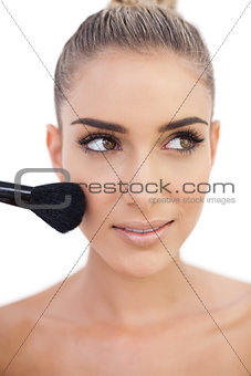 Happy woman applying powder on her cheeks