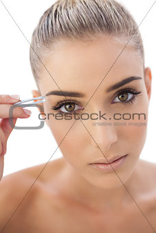 Focused woman plucking her eyebrows