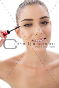 Happy woman applying mascara