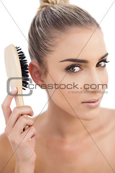 Thoughtful brunette holding a hairbrush