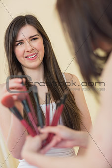 Happy girl choosing a makeup brush at sleepover