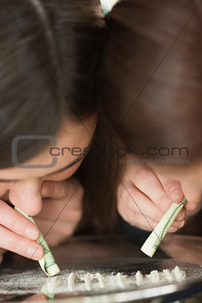 Two girls snorting an illegal white substance