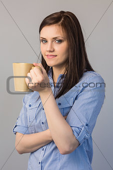 Smiling pretty brunette holding cup of coffee