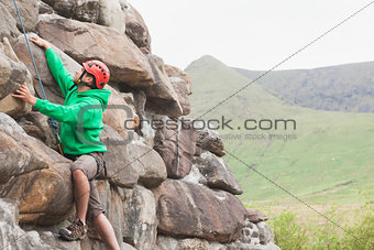 Focused man scaling a large rock face