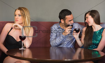 Blonde woman feeling alone as two people are flirting beside her