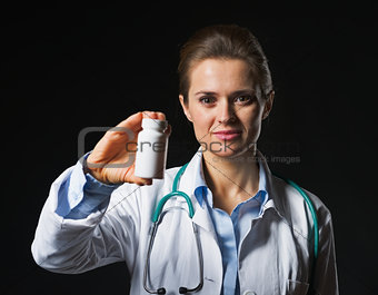 Doctor woman showing medicine bottle on black background