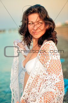 Happy girl in a white shawl on the beach.