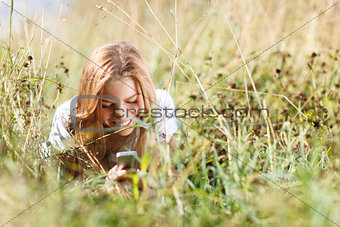 Girl is writing sms on the phone lying in grass