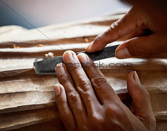 Hands woodcarver with the tool close-up