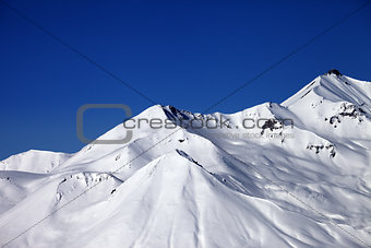 Snowy winter mountains and clear blue sky in sun day