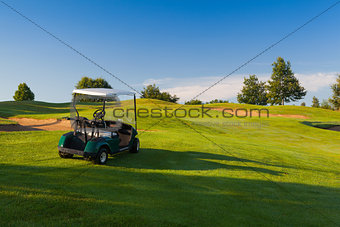 Green golf cart on the empty golf course