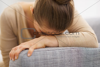 Frustrated young housewife sitting on sofa