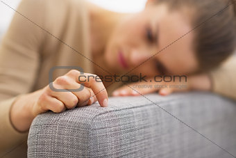 Closeup on hand of frustrated young housewife sitting on couch