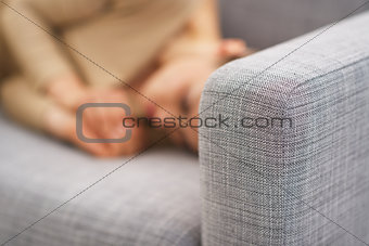 Closeup on couch and frustrated young housewife in background