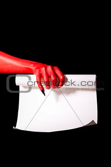 Red devil hand with black nails holding paper scroll 