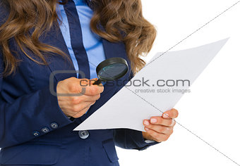 Closeup on business woman examining document using magnifying gl