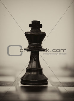 Black wooden chess king on chess board