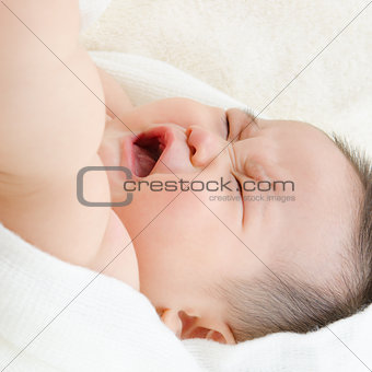 Asian baby boy crying on bed