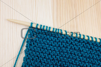 Garter stitch in teal yarn on knitting needle