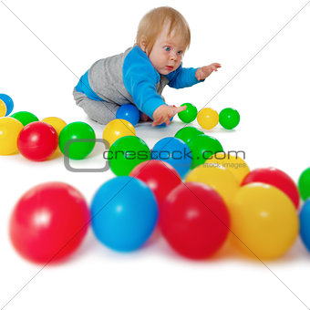 Comical child playing with colored plastic balls