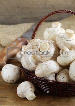 organic mushrooms (champignons) in a basket on a wooden background