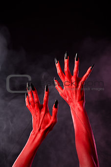 Red devil hands with black sharp nails, extreme body-art 