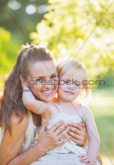 Baby embracing mother outdoors
