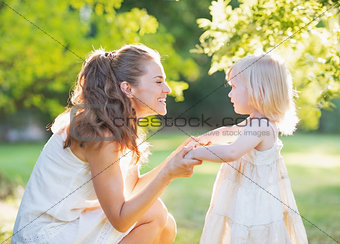 Happy mother playing with baby outdoors
