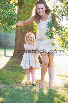 Portrait of happy mother and baby near tree