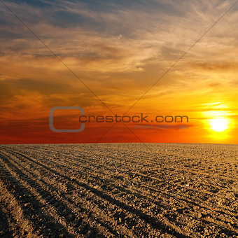 red sunset over ploughed farm field