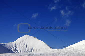 Ski slope with ropeway at sunny winter day